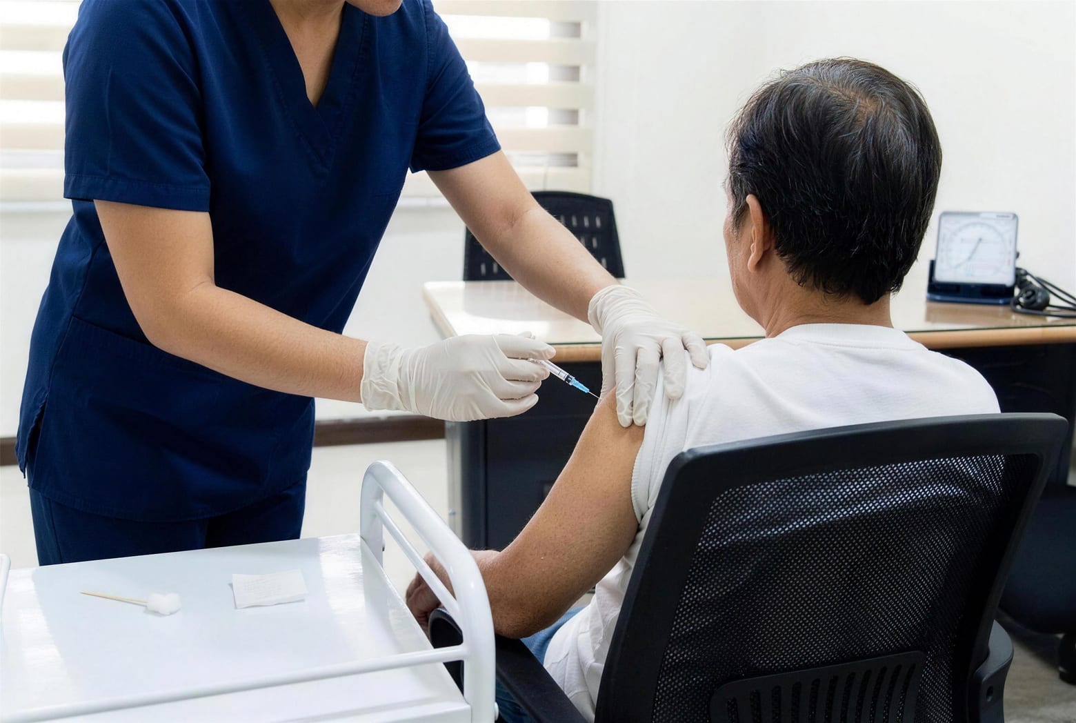 A nurse giving a vaccination into the upper arm of a seated older patient.